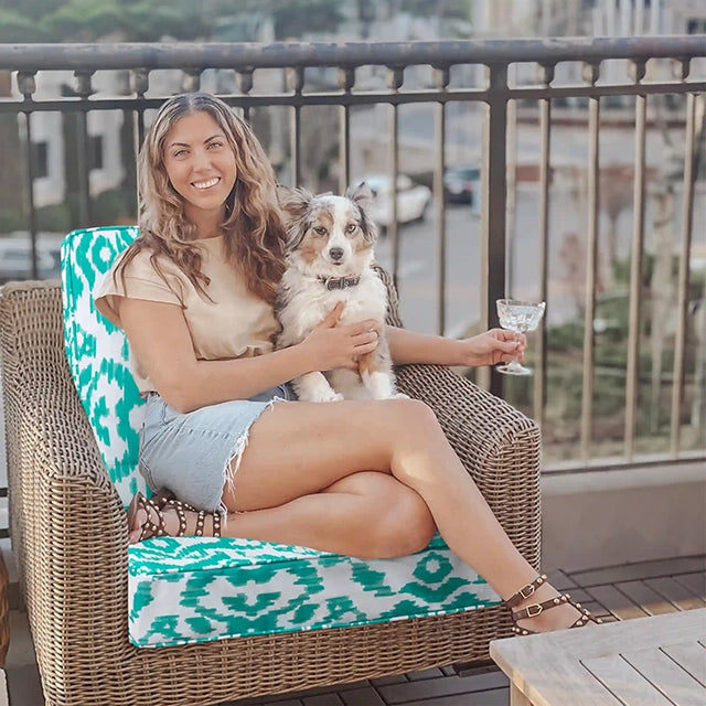 A woman sitting on the balcony sofa holding her pet dog